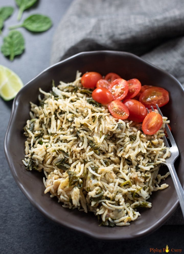 Palak Rice served in a bowl along with cherry tomatoes