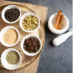 Whole spices in small white bowls