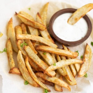 French Fries with a fry dipped in a yogurt dipping sauce