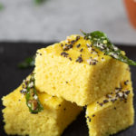 Khaman Dhokla with tempered with green chili and curry leaves stacked.