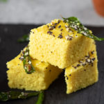 Khaman Dhokla with tempered with green chili and curry leaves stacked.