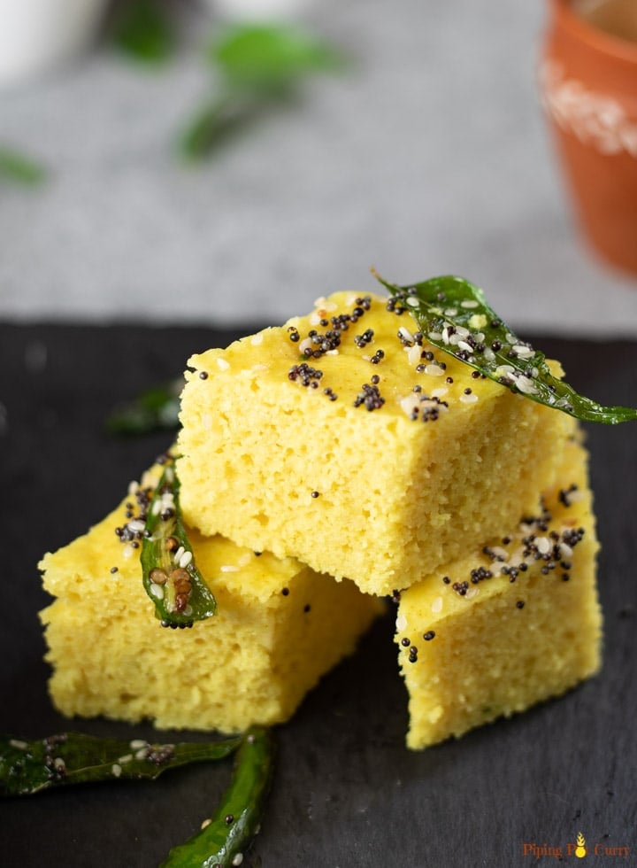 Khaman Dhokla with tempered with green chili and curry leaves stacked.