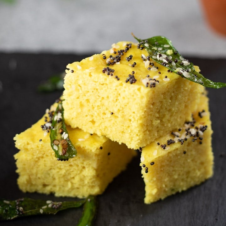 Khaman Dhokla with tempered with green chili and curry leaves stacked.