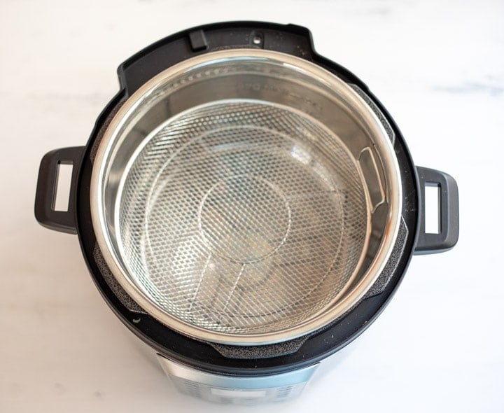 Pressure cooker with a trivet and a mesh basket on the trivet