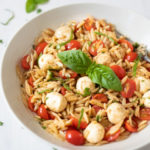 Caprese Orzo Pasta Salad in a white bowl garnished with balsamic and basil