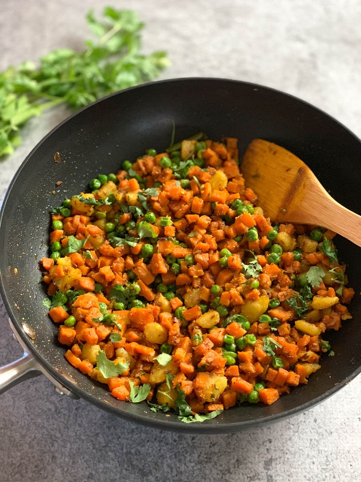 Aloo gajar matar cooked in a pan garnished with cilantro.