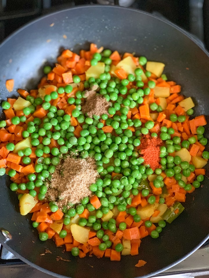 Cook carrots, potatoes and peas in a wok