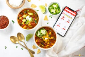 Two bowls of taco soup along with toppings spread out