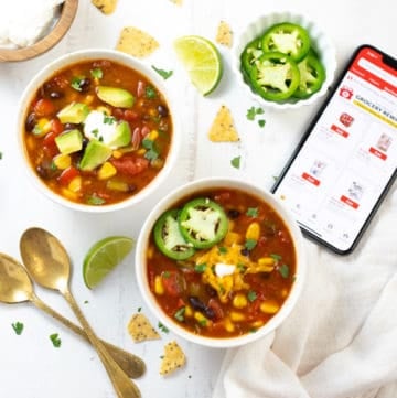 Two bowls of taco soup along with toppings spread out