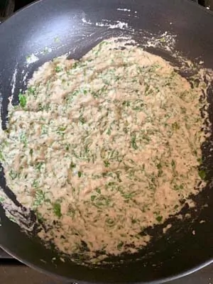 White curry sauce with green leaves in a wok