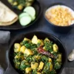Aloo Palak (Potatoes & Spinach Stir Fry) in a cast iron skillet with raita and roti