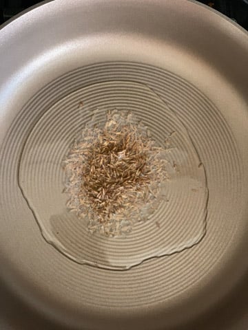 Oil and cumin seeds in a pan