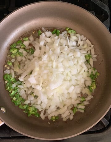 Onions and jalapeno in a pan to be sautéed