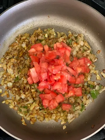 Tomatoes over sautéed onions in a pan
