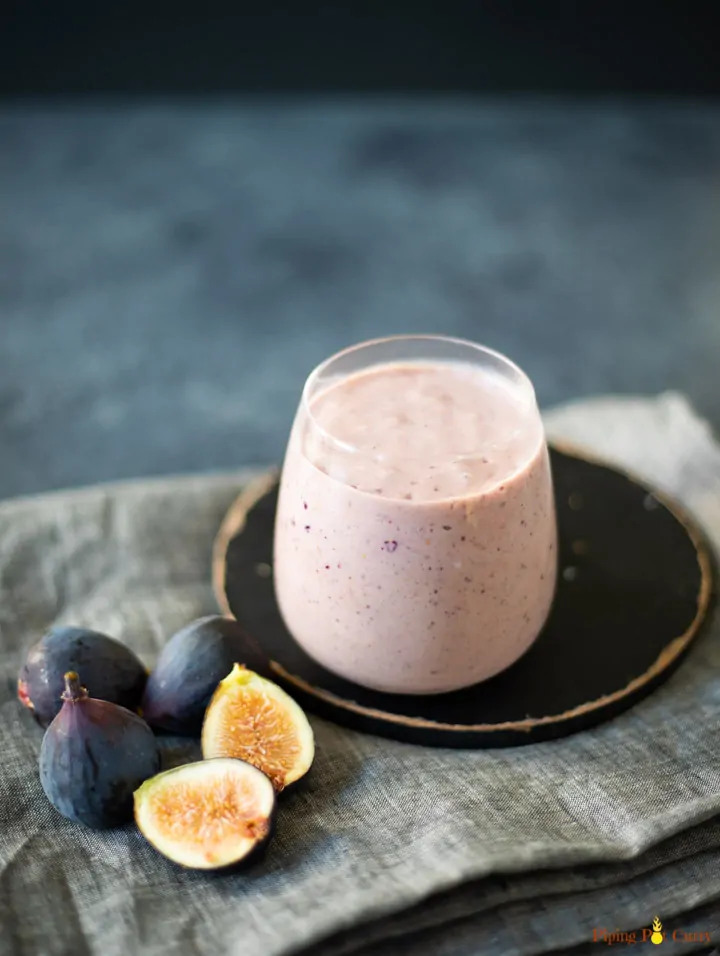 Fig smoothie in a glass with figs lying around