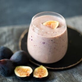 Fig smoothie with some figs lying beside the glass