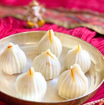Ukadiche Modak (sweet rice dumplings) in a plate and lord Ganesha idol in the back