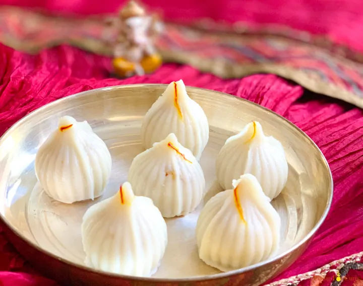 Ukadiche Modak (sweet rice dumplings) in a plate and lord Ganesha idol in the back