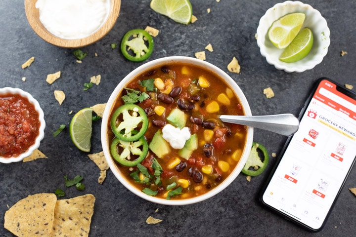 A bowl of taco soup with lots of toppings on the side