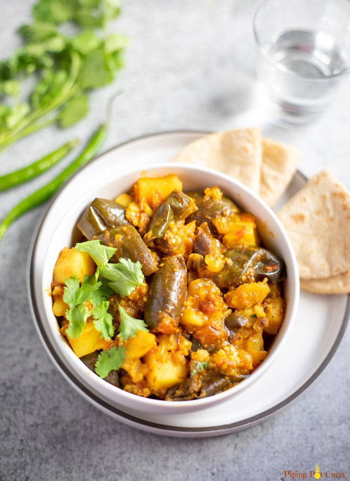 Aloo Baingan (potato and eggplant curry) in a white bowl with roti Indian flatbread