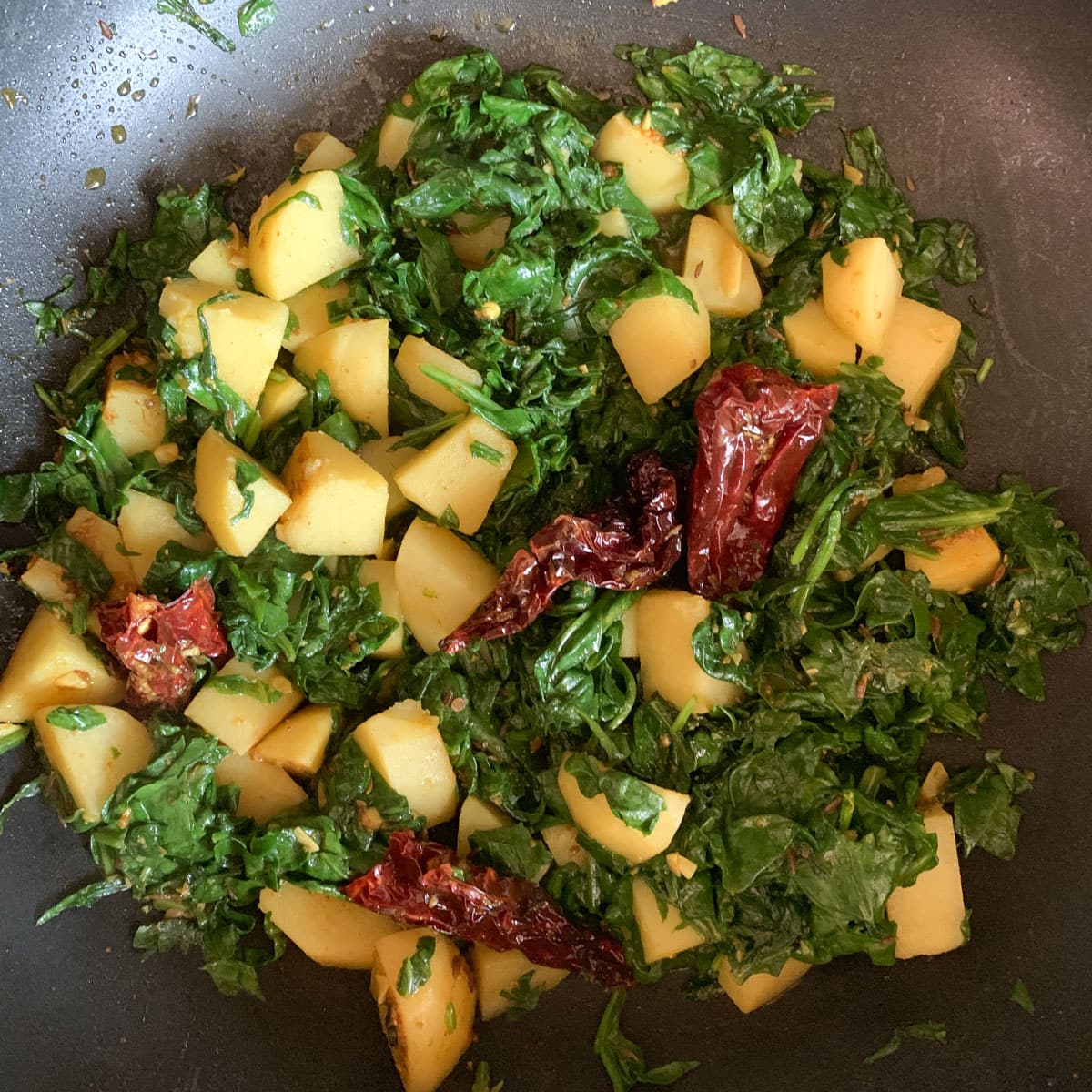 Spinach and potato stir fry (aloo palak) in a pan. 