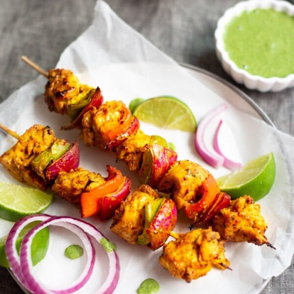 Chicken Tikka Kebab garnished with onions and green chutney on side