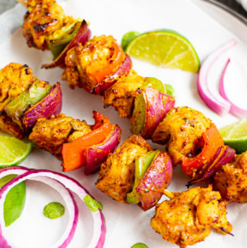 Chicken Tikka Kebab garnished with onions and green chutney on side