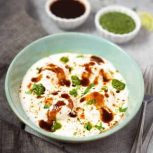 Dahi vada chaat with chutneys in small white bowls