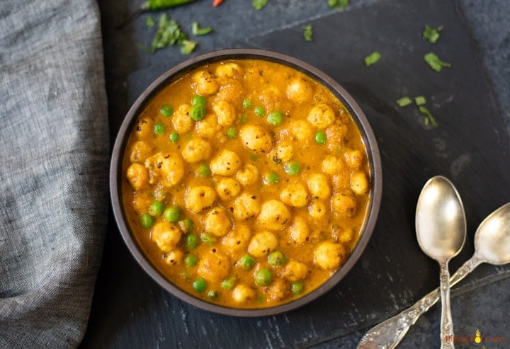 Green Peas and Foxnuts curry (Matar Makhana) in a bowl with 2 spoons