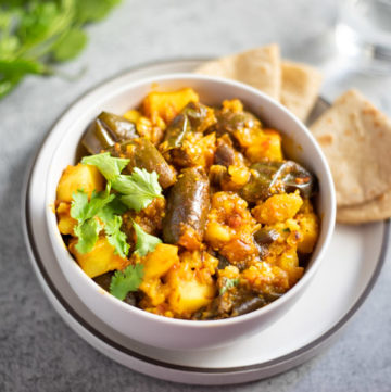 Aloo Brinjal (potato and eggplant curry) in a white bowl with roti Indian flatbread
