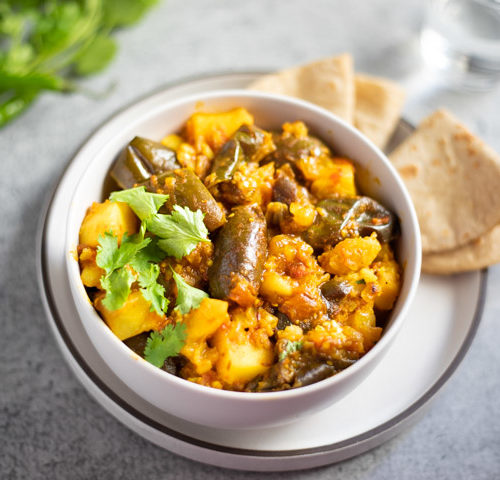 Aloo Brinjal (potato and eggplant curry) in a white bowl with roti Indian flatbread