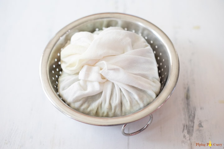 A white muslin cloth filled with lentils in a steel colander