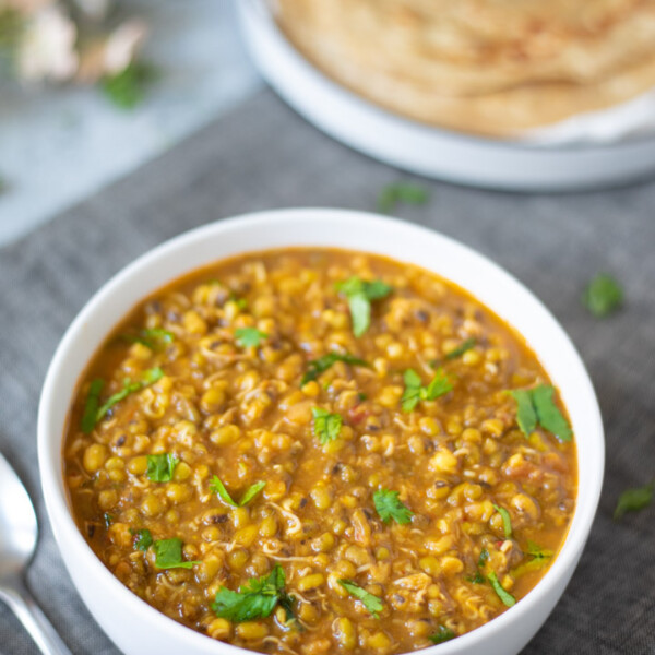 Moong Sprouts Curry in a whole bowl with parathas in a plate