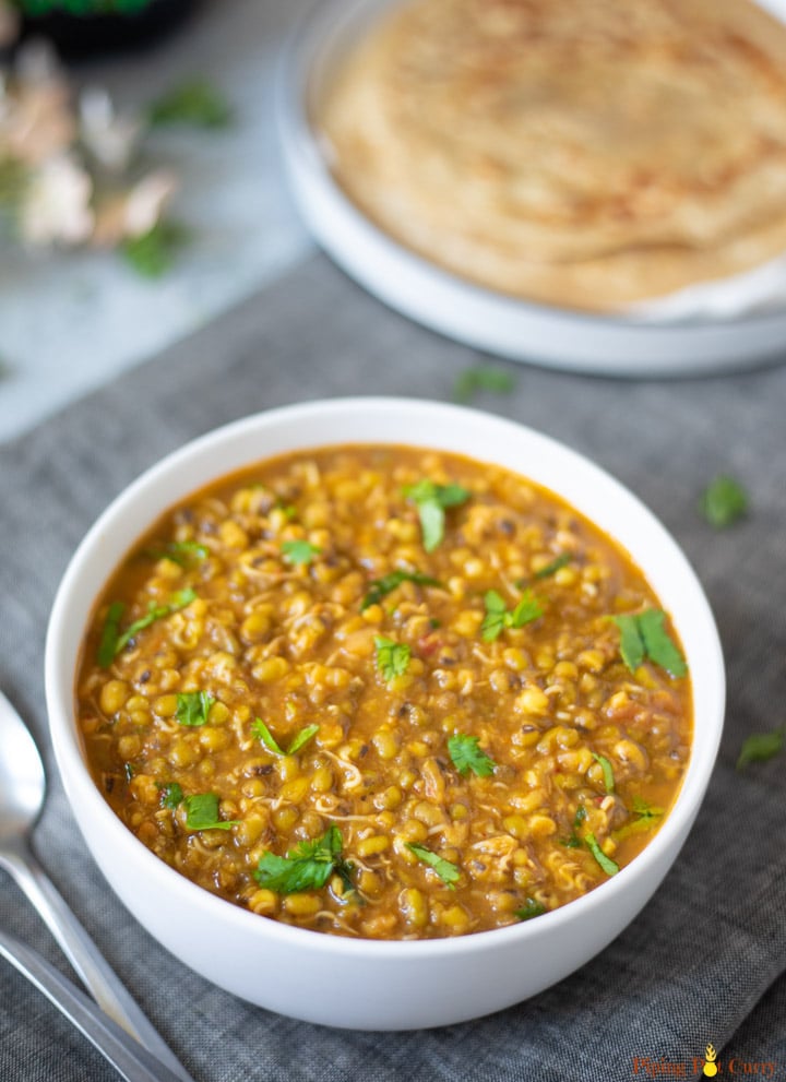 Moong Sprouts Curry in a whole bowl with parathas in a plate