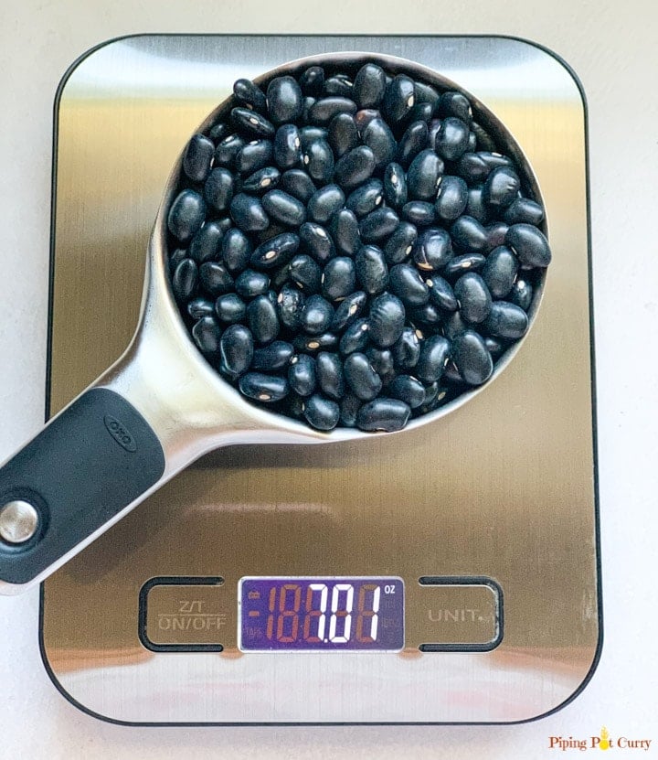 black beans in a measuring cup on a metal food scale