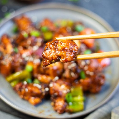Fried spicy chicken closeup in chopsticks
