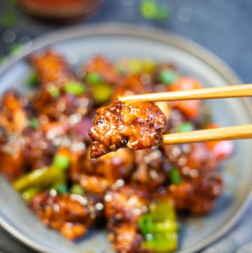 Crispy Saucy Chilli Chicken piece in chopsticks