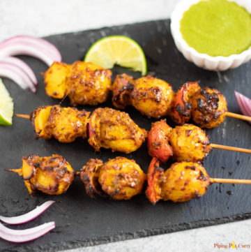 Tandoori Aloo Skewers along with green chutney, onions and lime