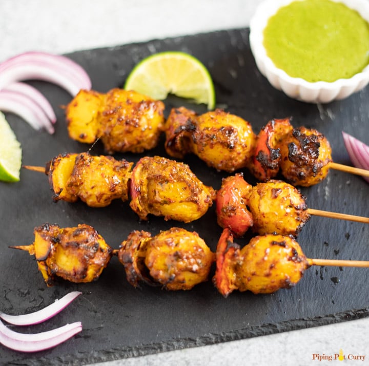 Tandoori Aloo Skewers along with green chutney, onions and lime