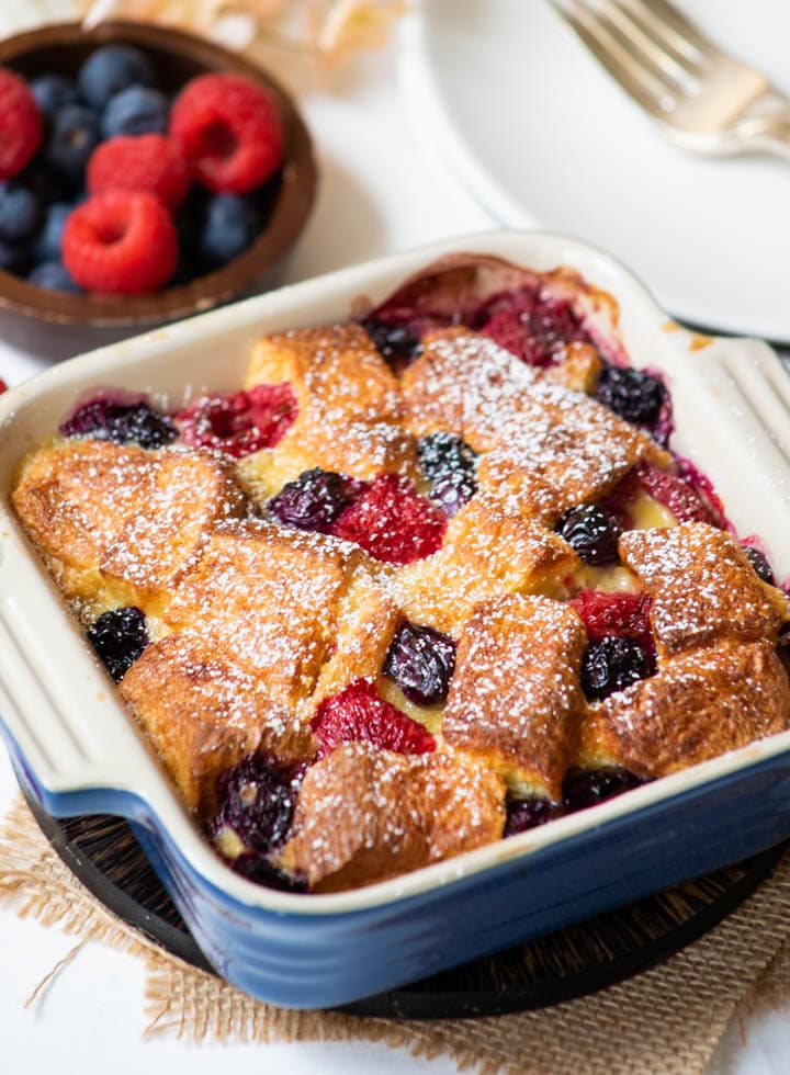 Berry Bread Pudding in a baking pan with fresh berries on the side