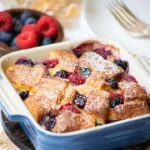Berry Bread Pudding in a baking pan with fresh berries on the side