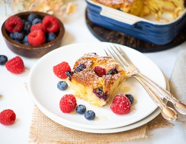 Berry Bread pudding served in a white plate with fresh berries on the side
