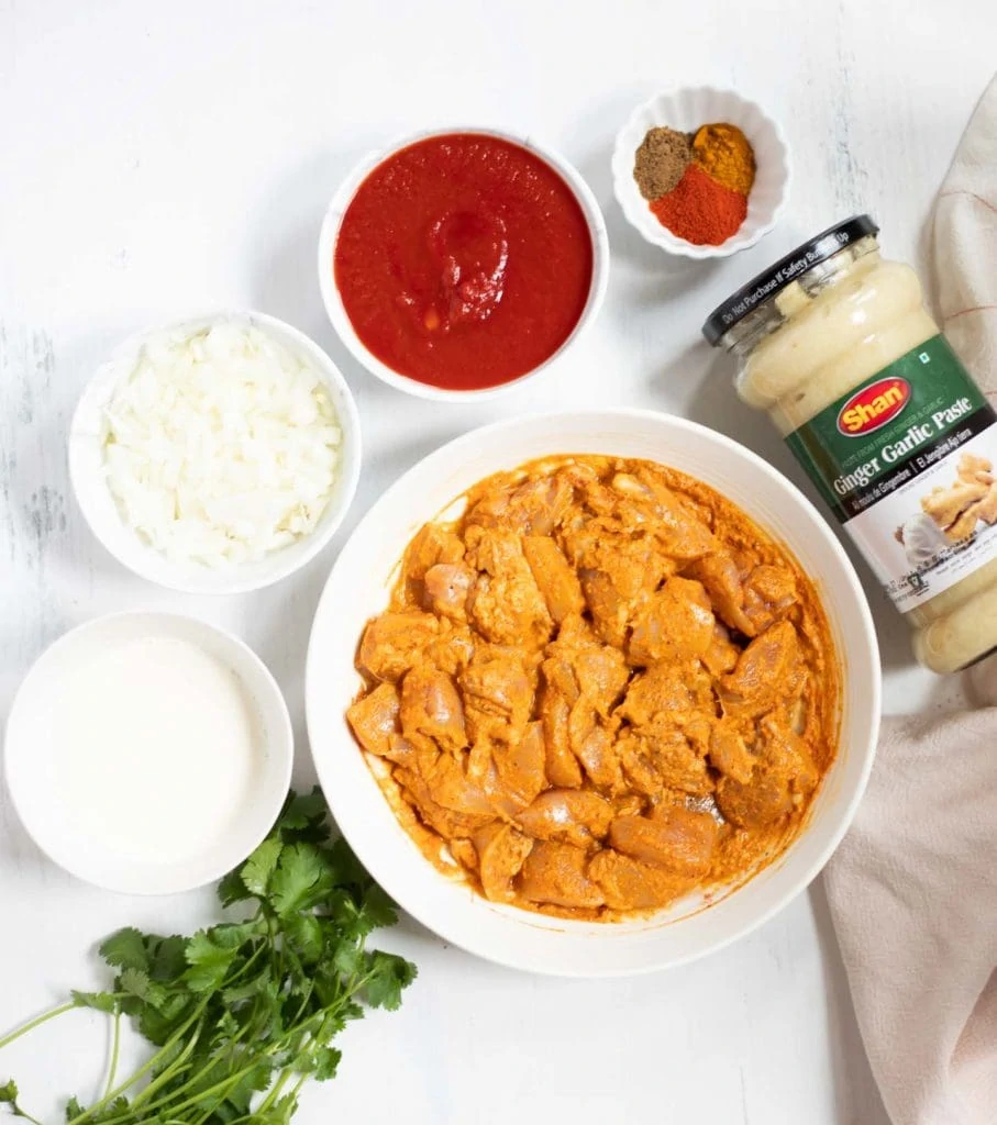 Ingredients such as marinated chicken, onions, tomato, ginger garlic, cilantro and spices