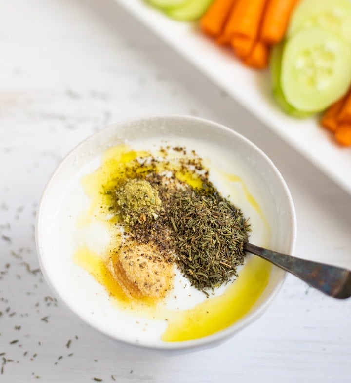 Yogurt topped with some herbs in a white bowl