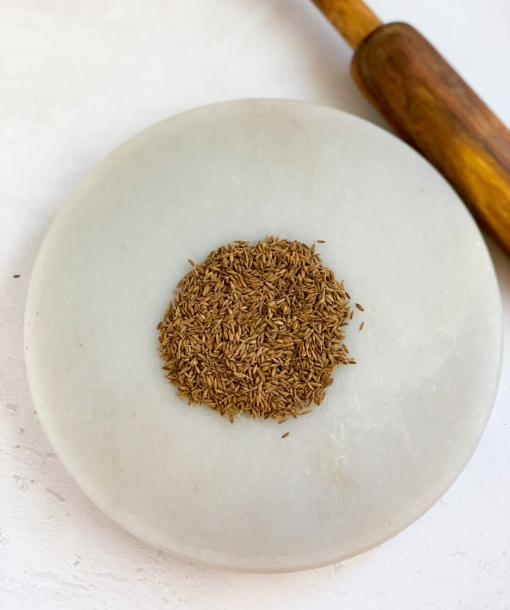 How to make roasted cumin powder - Piping Pot Curry-2 Roasted Cumin seeds on a marble base and a rolling pin (belan)