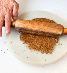 Some ground cumin on a marble with a rolling pin