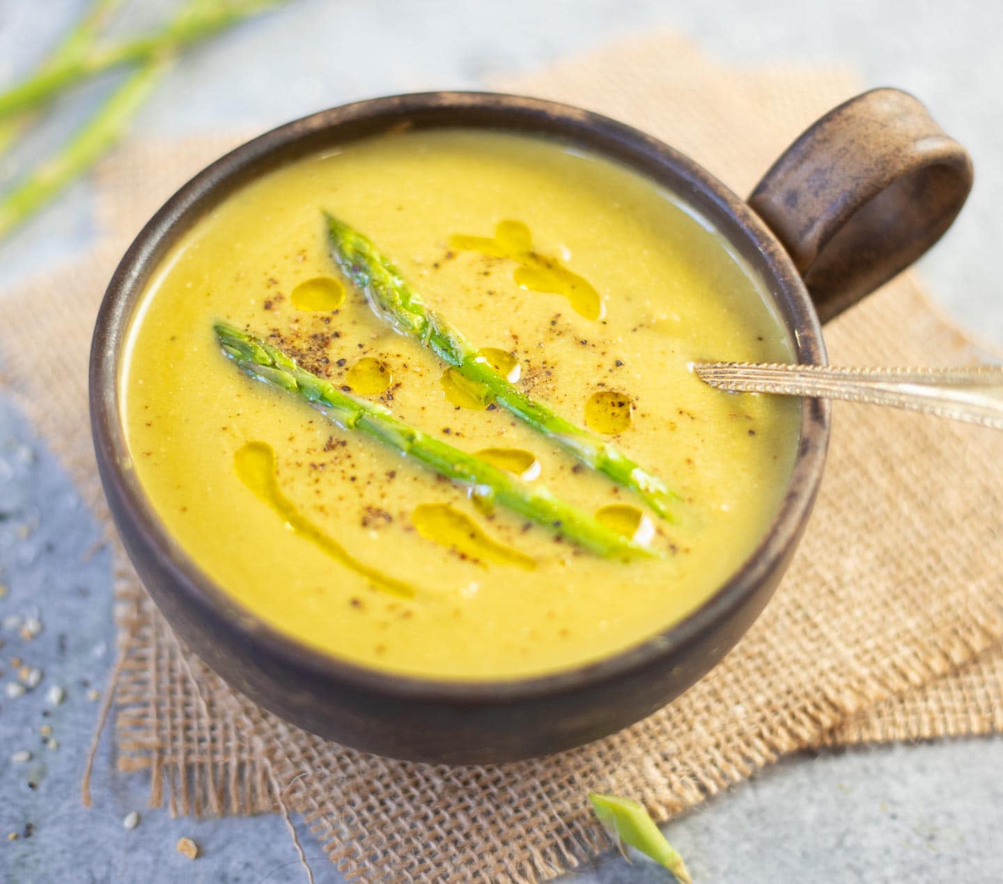 Asparagus soup topped with olive oil and 2 stalks of asparagus and black pepper