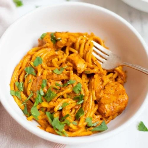 Chicken Tikka Spaghetti garnished with cilantro in a white bowl