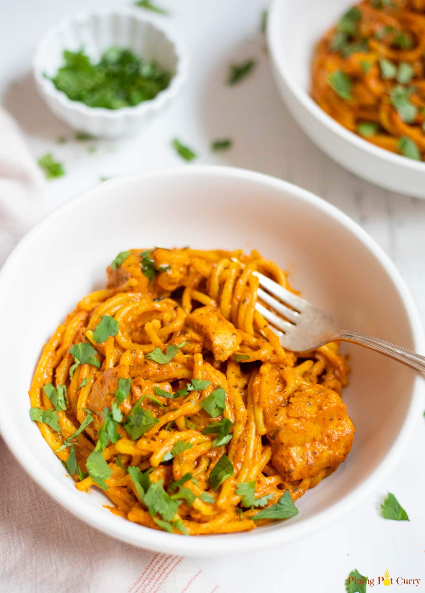 indian style spaghetti with chicken in white bowls garnished with cilantro