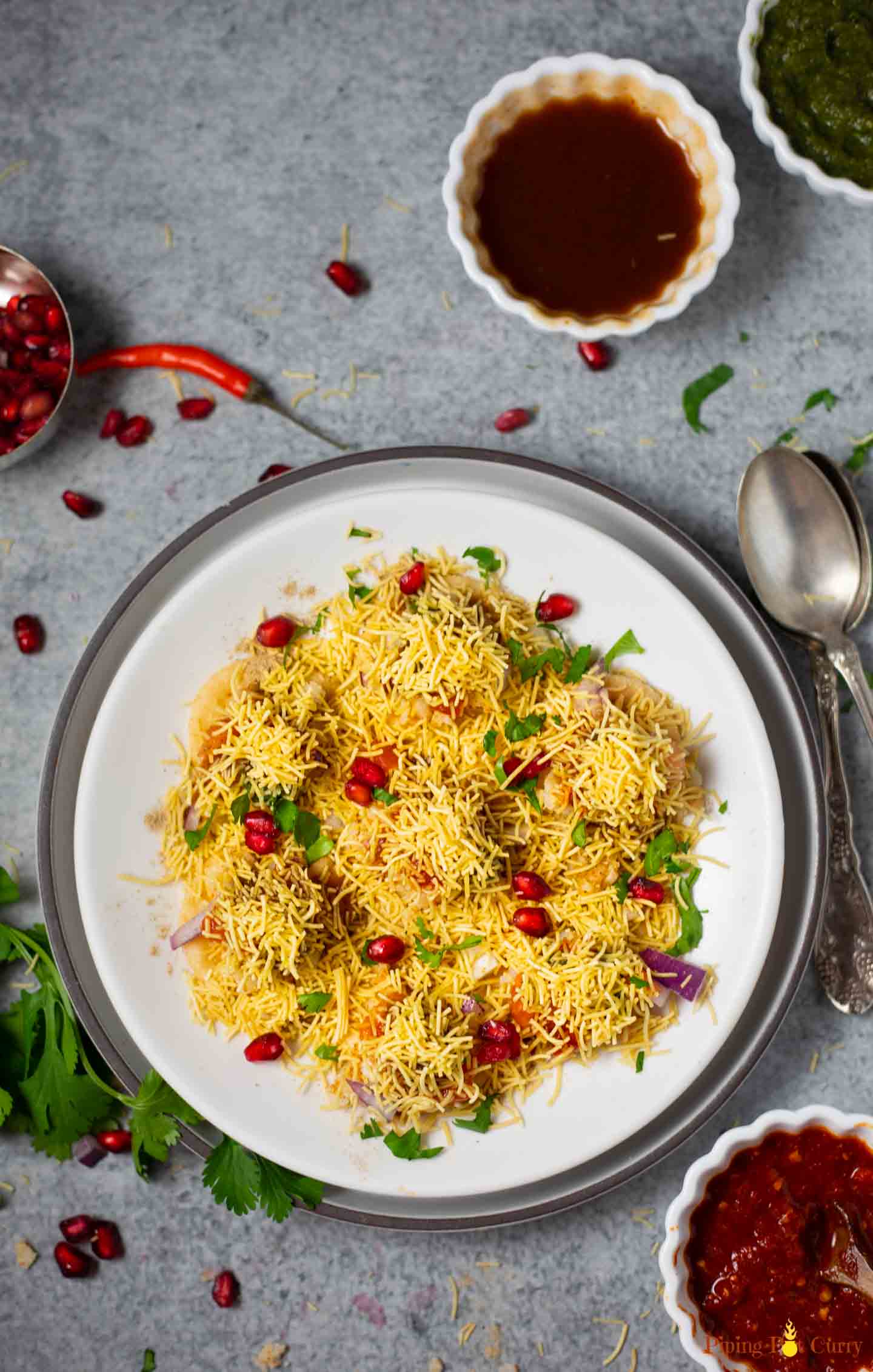 Sev Puri garnished with pomegranate seeds and cilantro served in a plate 